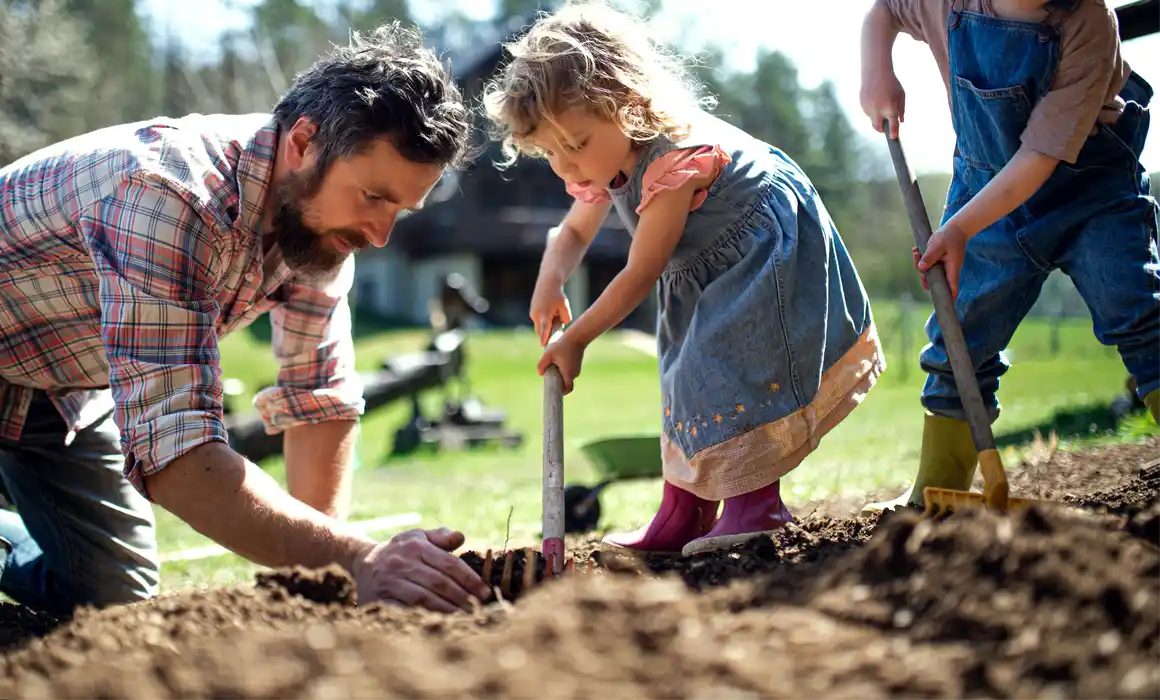 Father with two kids planting in soil