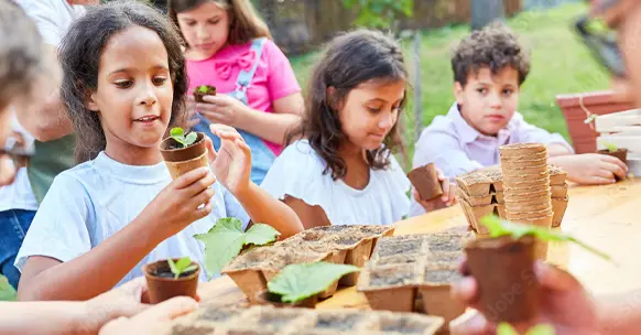 Children planting in paper pots