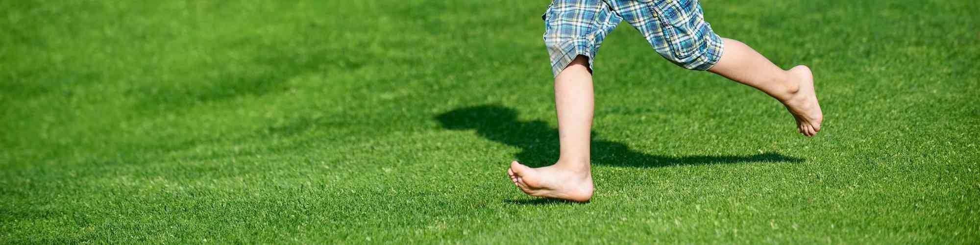 Happy boy running at the green golf course at sunny day